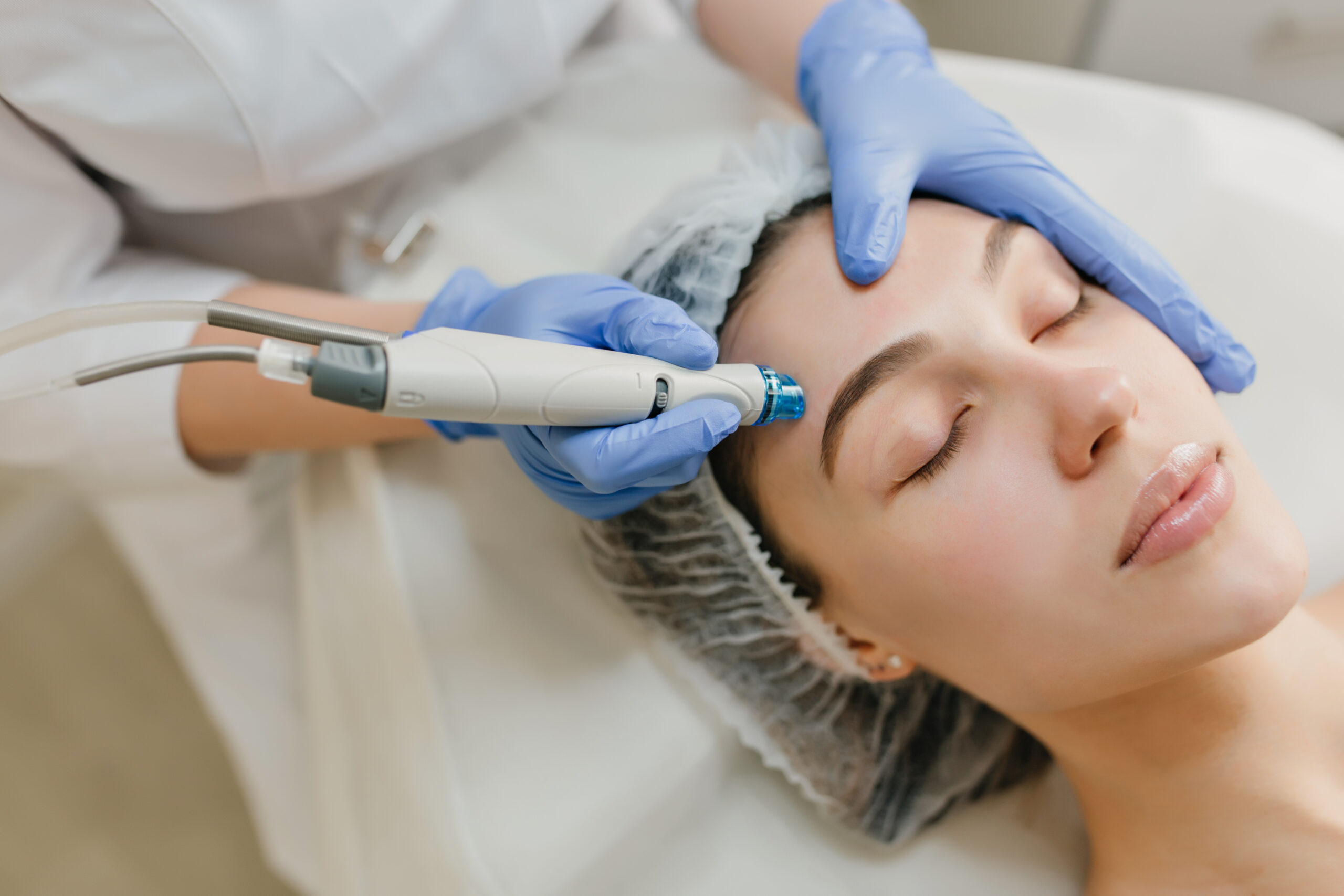 Traitement du visage avec un appareil d'hydrodermabrasion pour exfoliation et soins de la peau dans un institut de beauté.